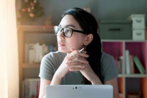 Woman thoughtful about work at home office desk laptop