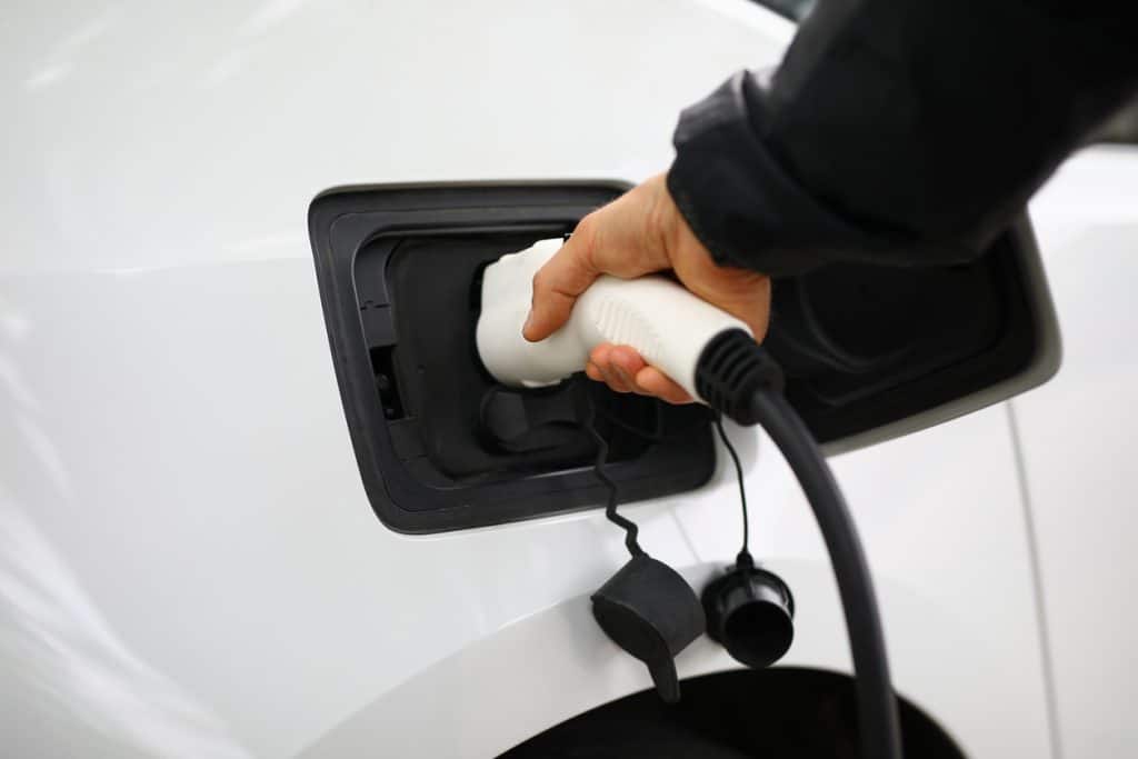 Driver inserts electric charger into vehicle